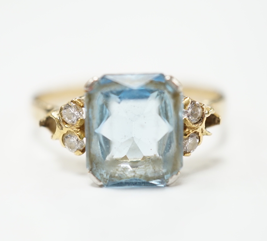 A yellow metal, single stone aquamarine and four stone diamond chip set dress ring, size M, gross weight 2.2 grams.